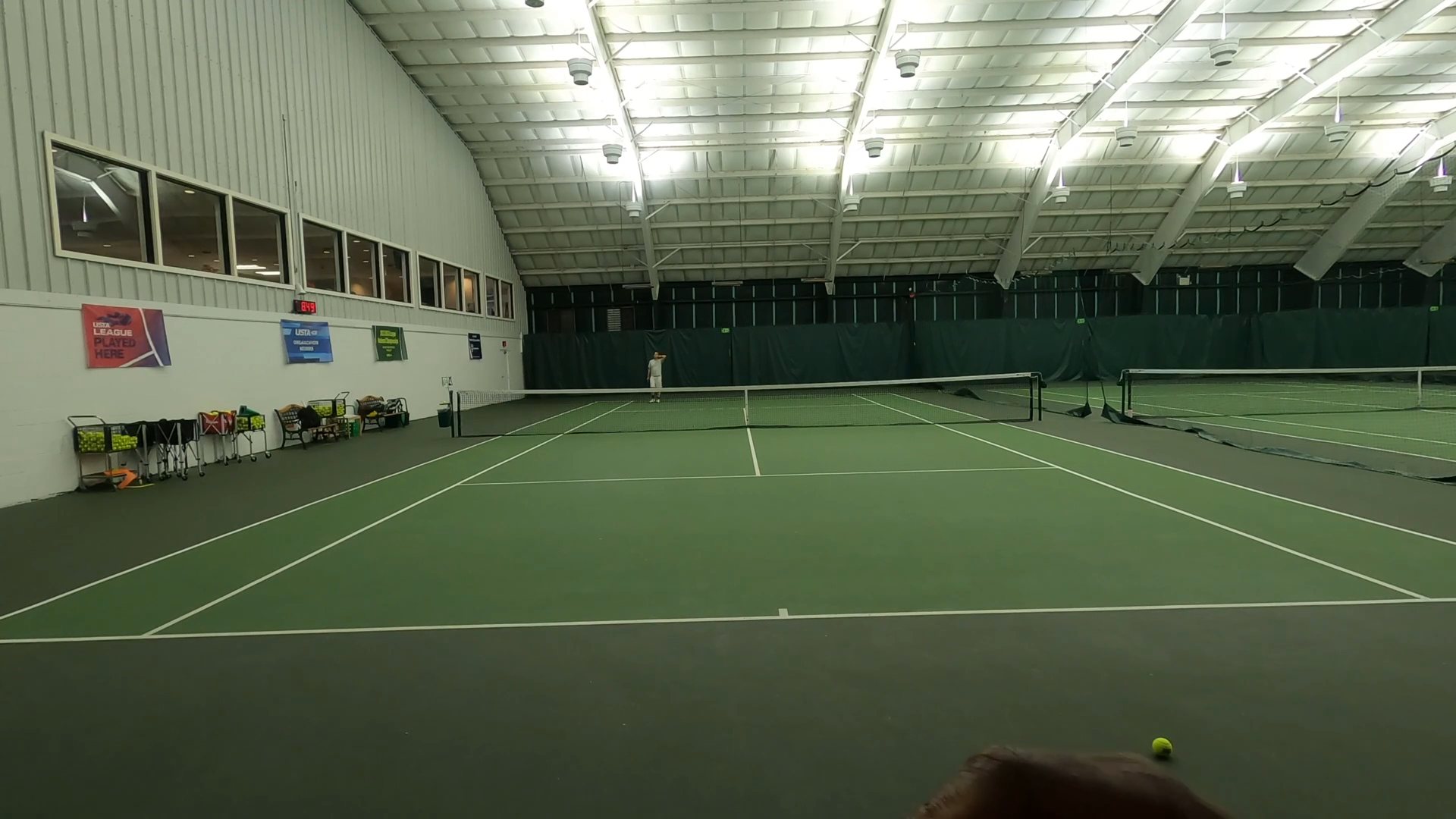 A recorded match seen from behind the near baseline, with the whole court in frame.